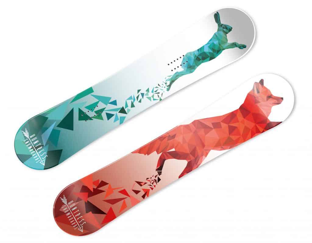 Two snowboards are seen. One has a geometric rabbit in blue and green. The other has a geometric fox in red and orange.